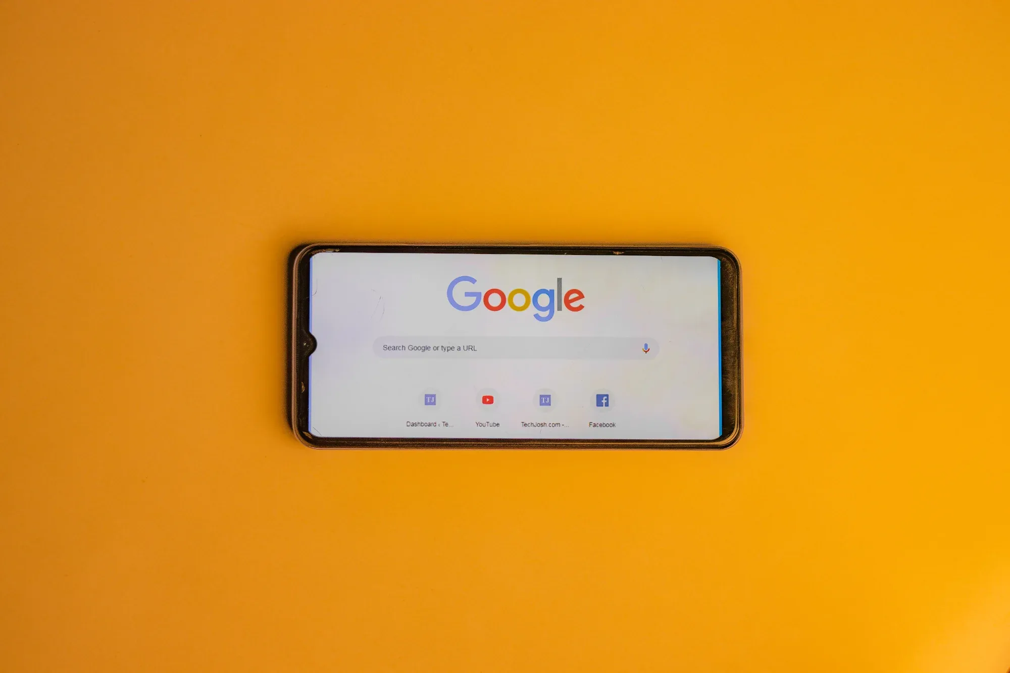 Téléphone et Google posé sur fond jaune.